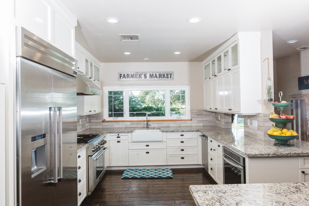 Example of a large country u-shaped dark wood floor eat-in kitchen design in Boston with a farmhouse sink, white cabinets, granite countertops, stainless steel appliances, an island, shaker cabinets, brown backsplash and matchstick tile backsplash