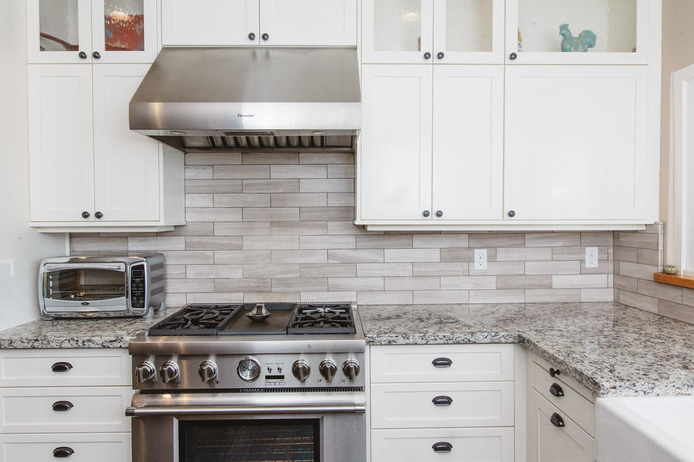 Example of a large country u-shaped dark wood floor eat-in kitchen design in Boston with a farmhouse sink, white cabinets, granite countertops, stainless steel appliances, an island, shaker cabinets, brown backsplash and matchstick tile backsplash
