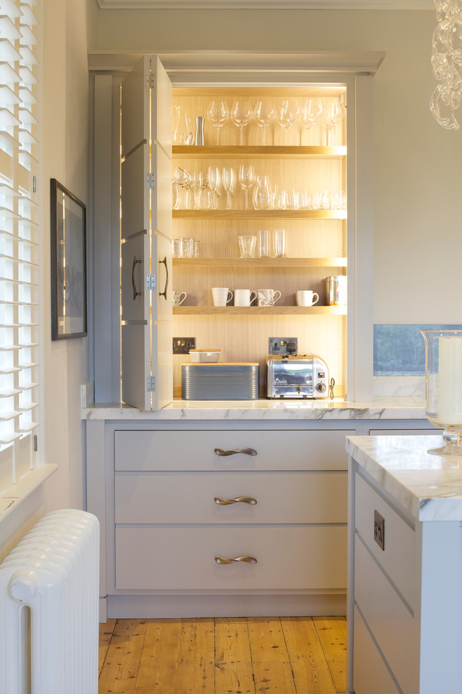 Imagen de cocina clásica renovada con armarios con paneles lisos, puertas de armario grises, encimera de mármol, una isla y suelo de madera clara