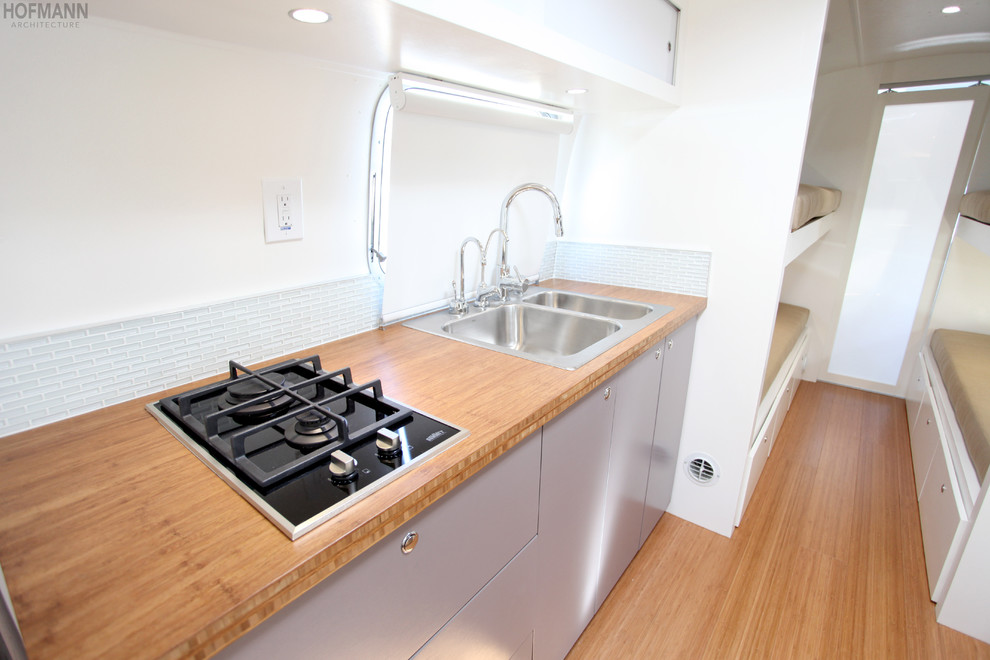 Example of a small trendy galley bamboo floor kitchen pantry design in Santa Barbara with a double-bowl sink, flat-panel cabinets, gray cabinets, wood countertops, blue backsplash, glass tile backsplash and stainless steel appliances