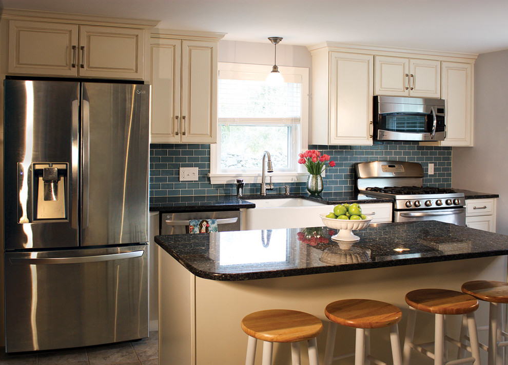 Example of a mid-sized beach style galley ceramic tile eat-in kitchen design in Boston with a farmhouse sink, raised-panel cabinets, white cabinets, granite countertops, blue backsplash, subway tile backsplash, stainless steel appliances and an island