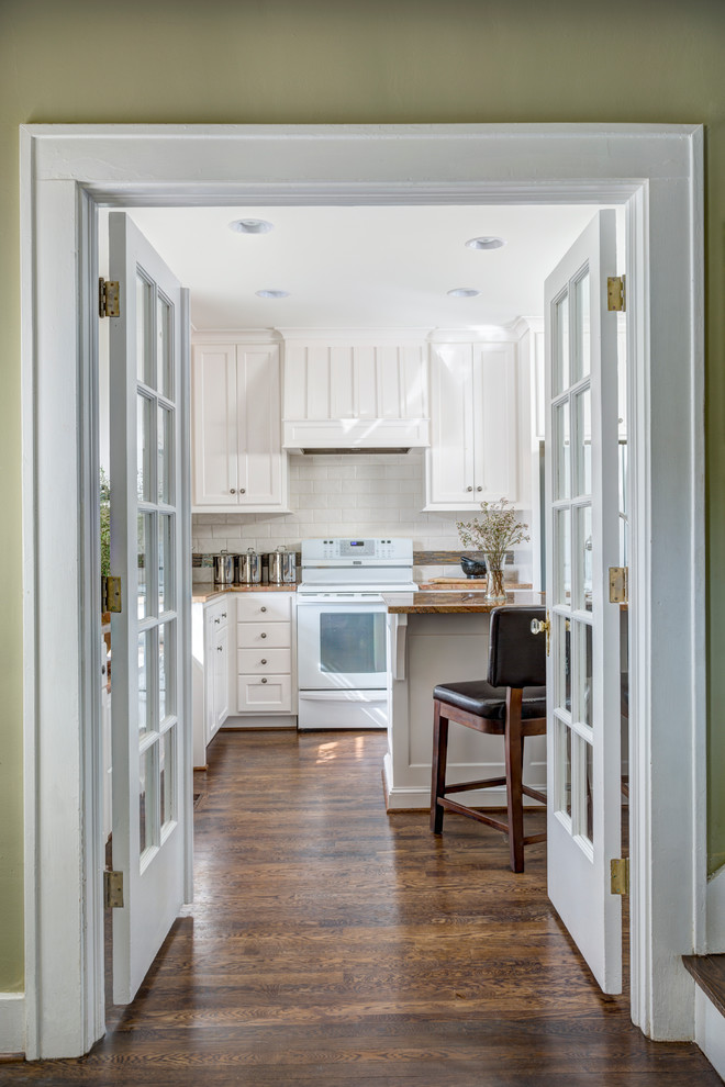 Inspiration for a classic kitchen in Kansas City with white cabinets, granite worktops, white splashback, ceramic splashback, white appliances, dark hardwood flooring and an island.