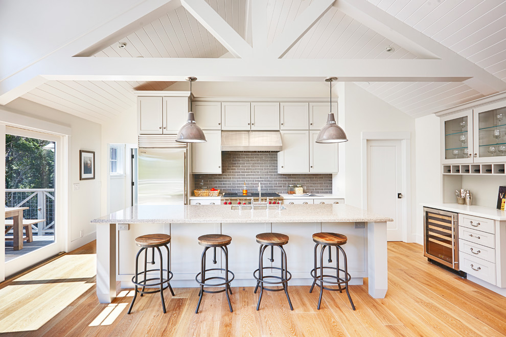 Large farmhouse galley medium tone wood floor kitchen photo in San Francisco with an undermount sink, shaker cabinets, white cabinets, granite countertops, gray backsplash, glass tile backsplash, stainless steel appliances and an island