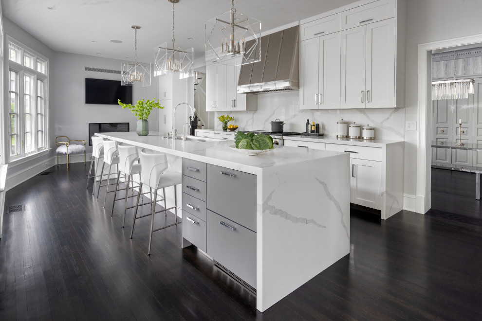 Design ideas for a contemporary galley kitchen in New York with a submerged sink, shaker cabinets, white cabinets, white splashback, stainless steel appliances, dark hardwood flooring, an island, brown floors and white worktops.