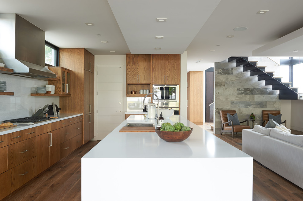 Inspiration for a large contemporary l-shaped medium tone wood floor and brown floor open concept kitchen remodel in San Diego with an undermount sink, flat-panel cabinets, medium tone wood cabinets, quartz countertops, white backsplash, porcelain backsplash, stainless steel appliances, an island and white countertops