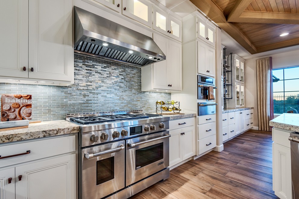 Moderne Küche mit Schrankfronten mit vertiefter Füllung, weißen Schränken, Küchenrückwand in Blau, Rückwand aus Stäbchenfliesen, Küchengeräten aus Edelstahl und braunem Holzboden in Philadelphia