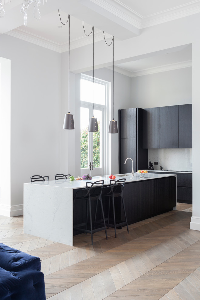 Imagen de cocina lineal contemporánea con fregadero integrado, armarios con paneles lisos, encimera de acrílico, salpicadero de losas de piedra y península