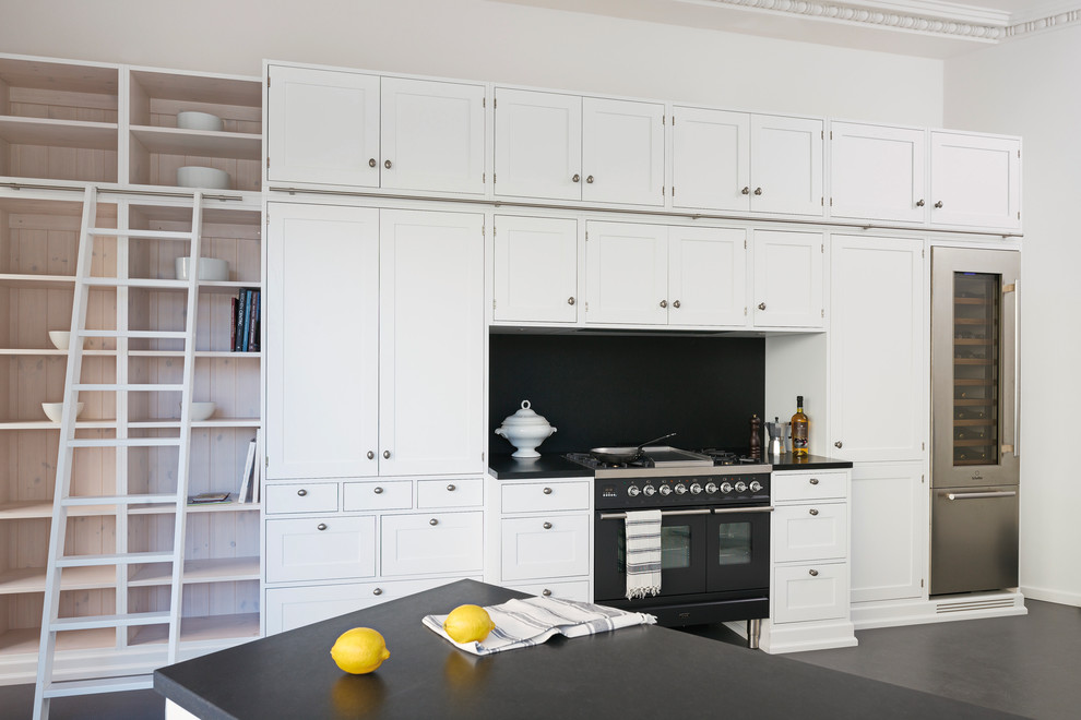 ヨーテボリにある高級な中くらいな北欧スタイルのおしゃれなキッチン (シェーカースタイル扉のキャビネット、黒いキッチンパネル、黒い調理設備、コンクリートの床) の写真