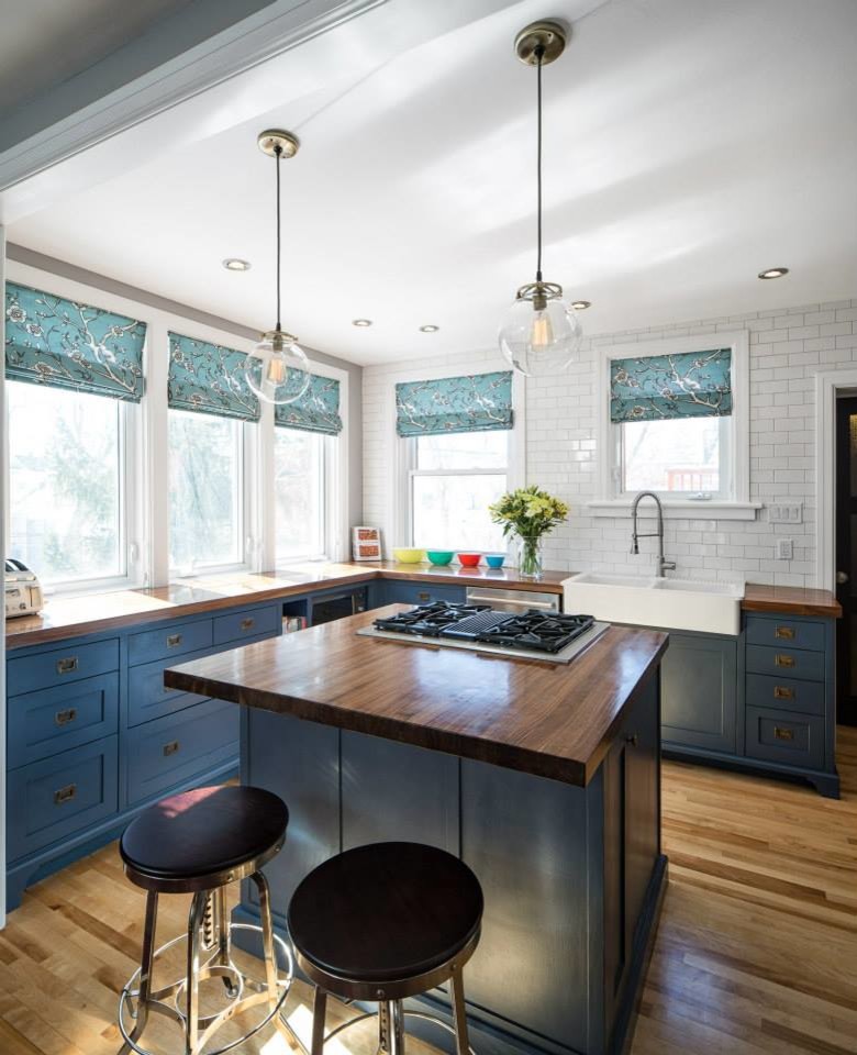 Large elegant l-shaped medium tone wood floor eat-in kitchen photo in Toronto with a farmhouse sink, shaker cabinets, blue cabinets, wood countertops, white backsplash, ceramic backsplash, stainless steel appliances and an island