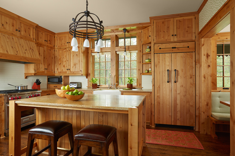 Foto på ett avskilt rustikt u-kök, med en rustik diskho, skåp i shakerstil, skåp i mellenmörkt trä, vitt stänkskydd, stänkskydd i tunnelbanekakel, integrerade vitvaror, mellanmörkt trägolv och en köksö