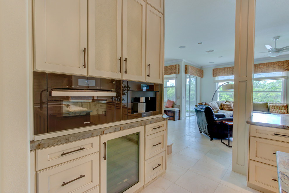 This is an example of a large traditional u-shaped enclosed kitchen in Other with a single-bowl sink, shaker cabinets, beige cabinets, granite worktops, beige splashback, glass tiled splashback, black appliances, porcelain flooring, an island, beige floors and beige worktops.