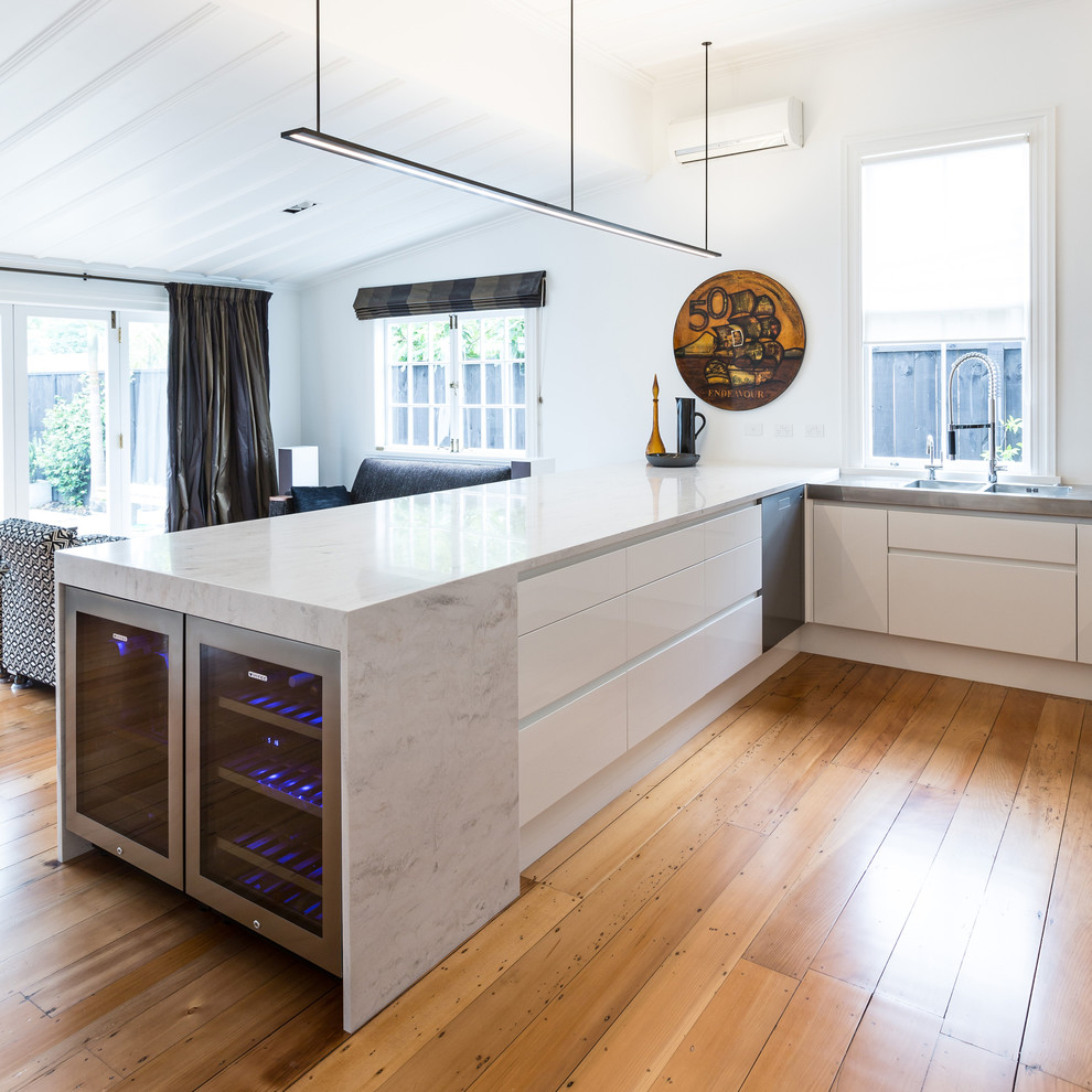 Contemporary u-shaped kitchen/diner in Auckland with a submerged sink, flat-panel cabinets, white cabinets, composite countertops, black splashback, mosaic tiled splashback and stainless steel appliances.