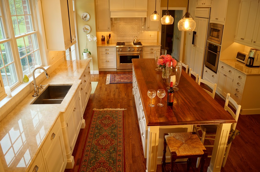 Eat-in kitchen - traditional l-shaped eat-in kitchen idea in Baltimore with an undermount sink, beige cabinets, wood countertops, beige backsplash, ceramic backsplash and stainless steel appliances