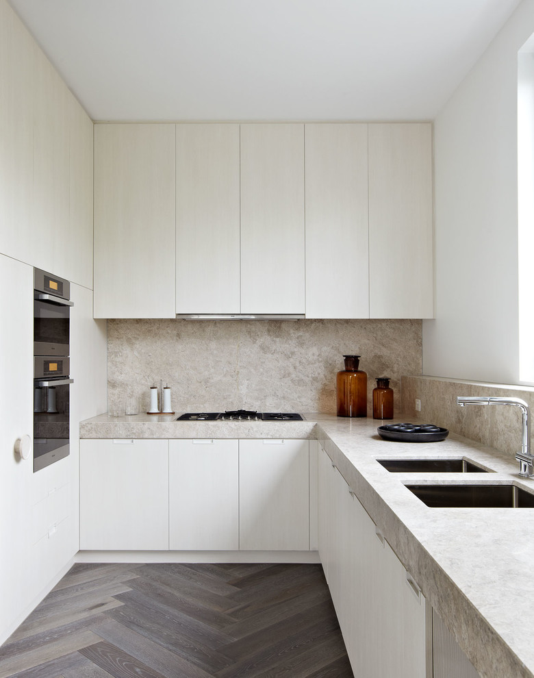 Modern inredning av ett l-kök, med en dubbel diskho, släta luckor, skåp i ljust trä, granitbänkskiva, beige stänkskydd, stänkskydd i sten, rostfria vitvaror och mörkt trägolv