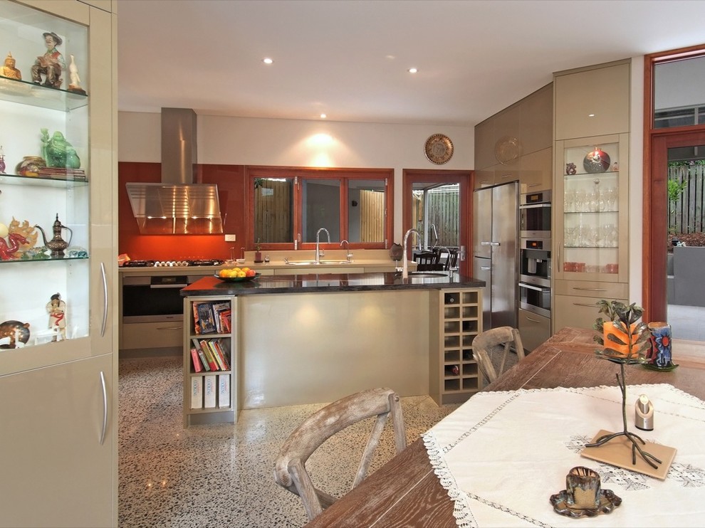 Große Moderne Wohnküche in U-Form mit flächenbündigen Schrankfronten, beigen Schränken, Küchenrückwand in Orange, Glasrückwand, Küchengeräten aus Edelstahl, Betonboden, Kücheninsel und Marmor-Arbeitsplatte in Brisbane