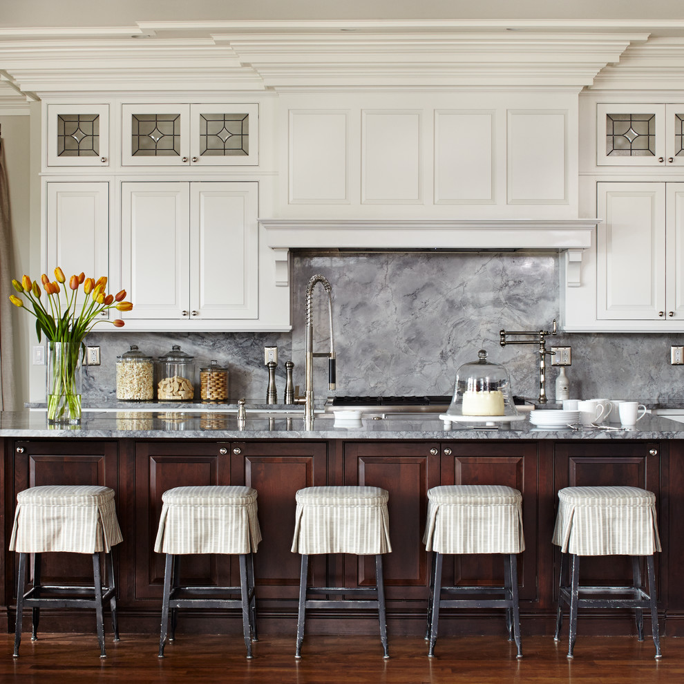 Zweizeilige Klassische Küche mit profilierten Schrankfronten, weißen Schränken, Küchenrückwand in Grau, Rückwand aus Stein, Küchengeräten aus Edelstahl, dunklem Holzboden, Kücheninsel, braunem Boden und grauer Arbeitsplatte in Denver