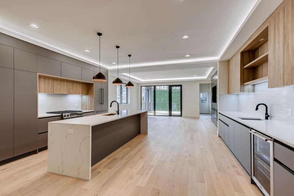 Inspiration for a large modern galley light wood floor eat-in kitchen remodel in Denver with a drop-in sink, flat-panel cabinets, dark wood cabinets, quartzite countertops, white backsplash, marble backsplash, stainless steel appliances, an island and white countertops