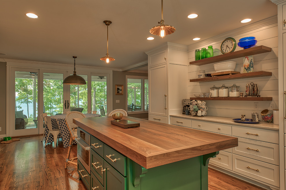 Bild på ett stort vintage vit vitt kök och matrum, med en rustik diskho, släta luckor, vita skåp, bänkskiva i kvartsit, vitt stänkskydd, stänkskydd i trä, integrerade vitvaror, mellanmörkt trägolv, en köksö och brunt golv