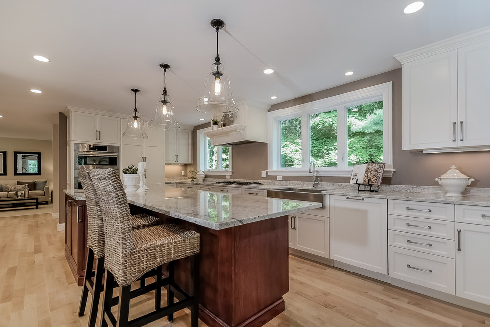 Inspiration for a large contemporary l-shaped light wood floor eat-in kitchen remodel in Boston with a farmhouse sink, shaker cabinets, white cabinets, stainless steel appliances and an island
