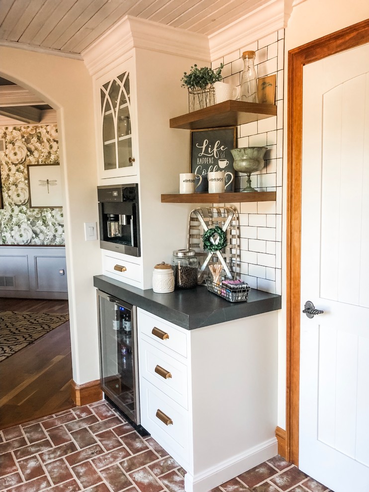 Idéer för ett mellanstort lantligt svart kök, med en rustik diskho, luckor med infälld panel, vita skåp, bänkskiva i täljsten, vitt stänkskydd, stänkskydd i tunnelbanekakel, rostfria vitvaror, tegelgolv, en köksö och rött golv