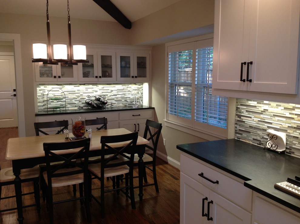 Klassisk inredning av ett kök och matrum, med en undermonterad diskho, skåp i shakerstil, vita skåp, granitbänkskiva, flerfärgad stänkskydd, stänkskydd i mosaik och rostfria vitvaror