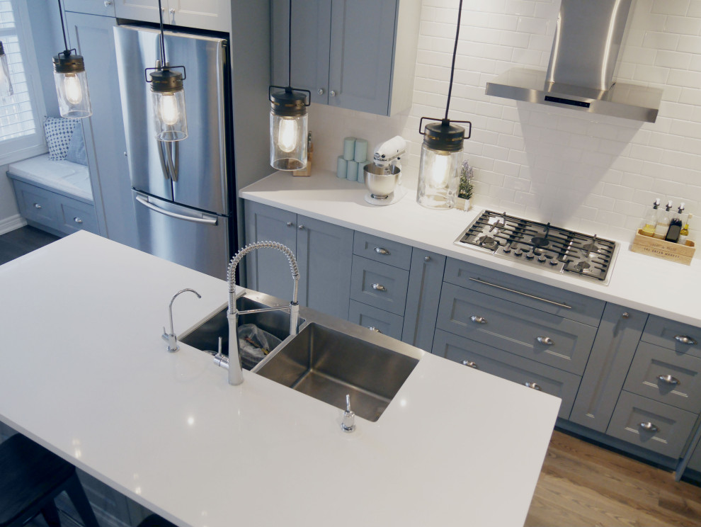 Exempel på ett mellanstort lantligt vit linjärt vitt kök och matrum, med en dubbel diskho, skåp i shakerstil, blå skåp, bänkskiva i kvartsit, vitt stänkskydd, stänkskydd i keramik, rostfria vitvaror, mörkt trägolv, en köksö och brunt golv