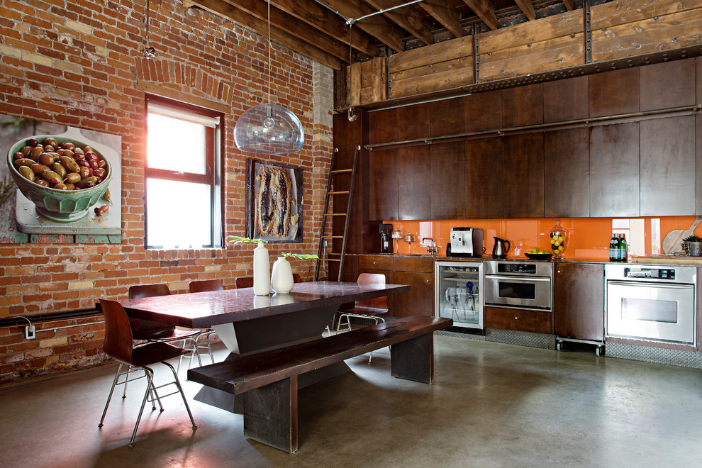 Idéer för att renovera ett industriellt grå linjärt grått kök och matrum, med släta luckor, skåp i mörkt trä, orange stänkskydd, glaspanel som stänkskydd, rostfria vitvaror, betonggolv och grått golv