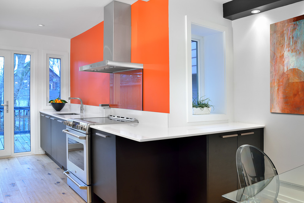 Foto di una cucina moderna con ante lisce, ante nere, top in quarzite, elettrodomestici in acciaio inossidabile e parquet chiaro