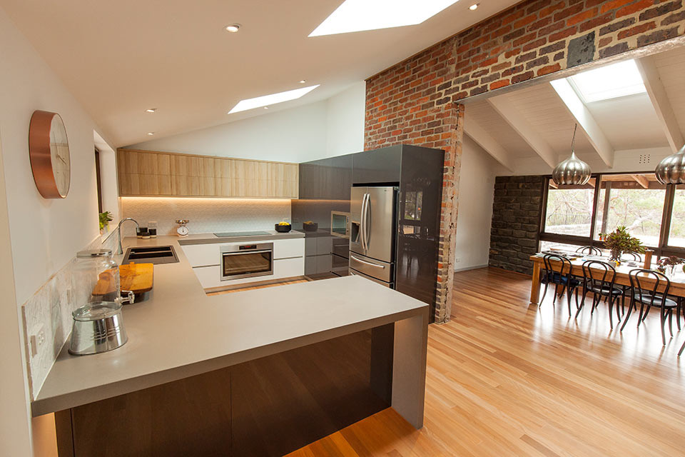Medium sized contemporary u-shaped kitchen/diner in Geelong with a double-bowl sink, white splashback, ceramic splashback, stainless steel appliances, light hardwood flooring, no island, flat-panel cabinets, white cabinets and engineered stone countertops.