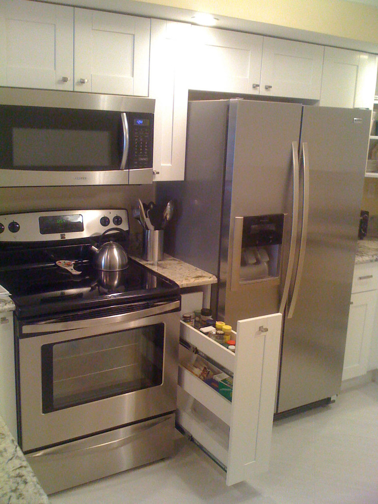 Klassische Wohnküche in U-Form mit Unterbauwaschbecken, Schrankfronten im Shaker-Stil, weißen Schränken, Granit-Arbeitsplatte und Küchengeräten aus Edelstahl in Miami