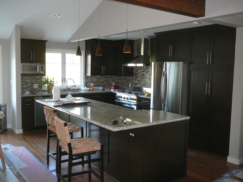 Example of a mid-sized arts and crafts l-shaped medium tone wood floor open concept kitchen design in Los Angeles with an undermount sink, shaker cabinets, dark wood cabinets, granite countertops, multicolored backsplash, mosaic tile backsplash, stainless steel appliances and an island