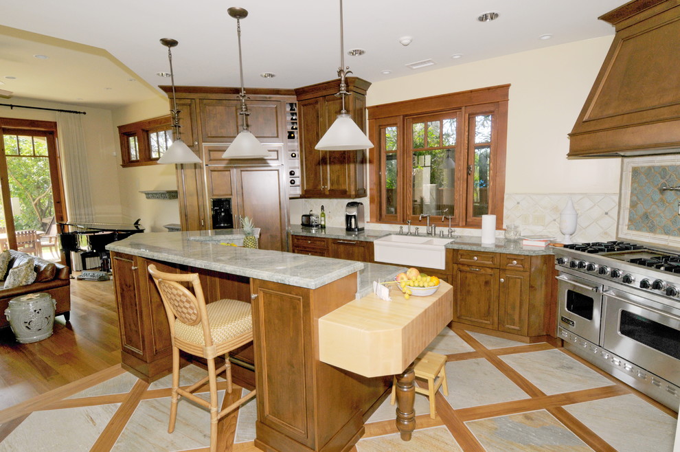 This is an example of a medium sized world-inspired l-shaped open plan kitchen in San Diego with light hardwood flooring, brown floors, a belfast sink, recessed-panel cabinets, medium wood cabinets, granite worktops, blue splashback, ceramic splashback, stainless steel appliances and an island.
