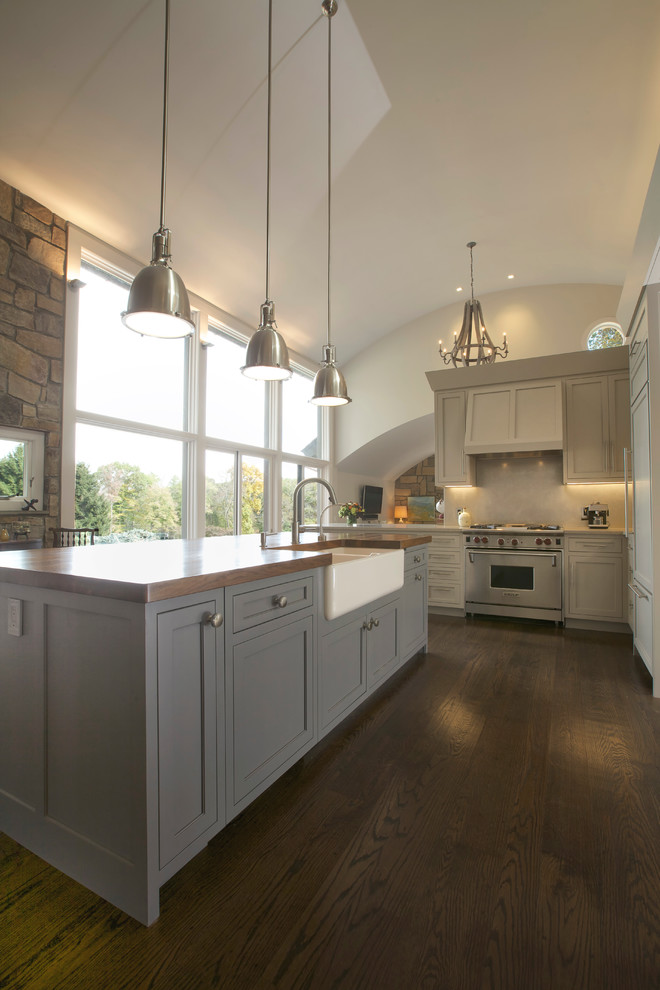 Example of a mid-sized arts and crafts u-shaped dark wood floor eat-in kitchen design in Phoenix with a farmhouse sink, shaker cabinets, gray cabinets, wood countertops, paneled appliances and an island