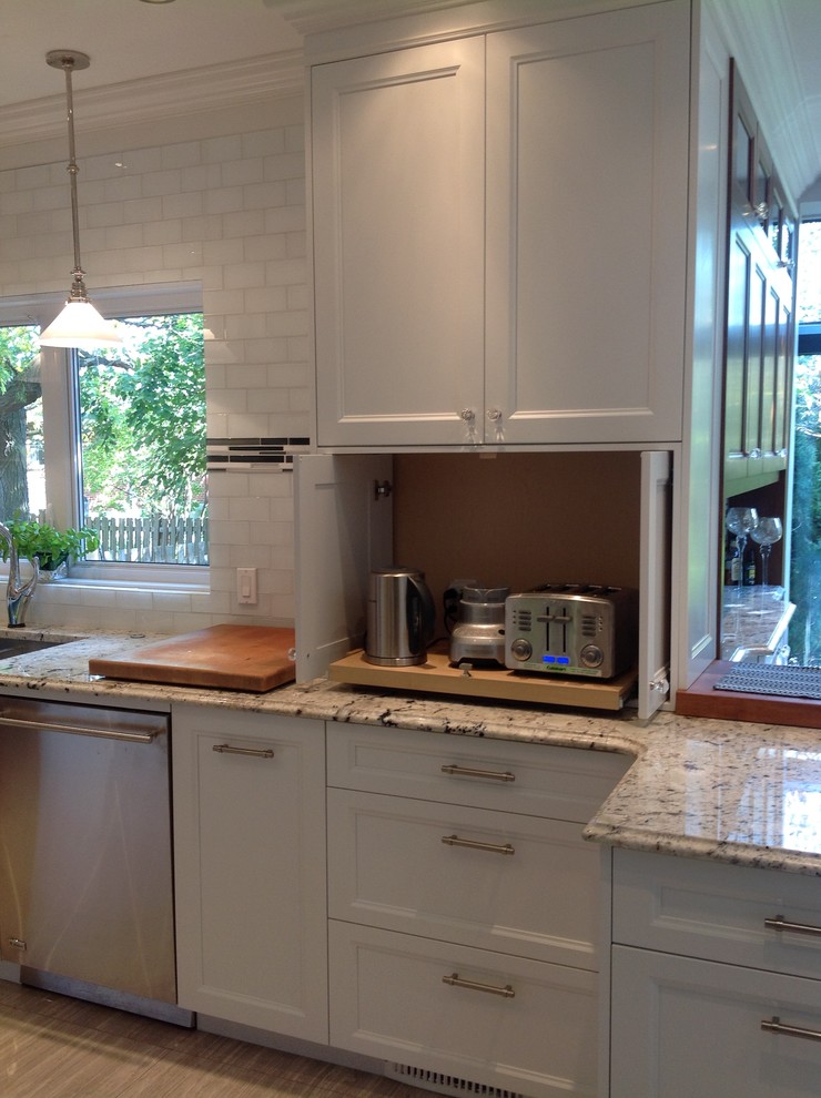 Geschlossene Klassische Küche in U-Form mit Unterbauwaschbecken, Schrankfronten im Shaker-Stil, weißen Schränken, Granit-Arbeitsplatte, Küchenrückwand in Weiß, Rückwand aus Glasfliesen und Küchengeräten aus Edelstahl in Montreal