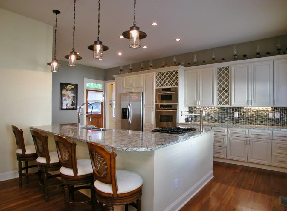 Large ornate l-shaped medium tone wood floor and brown floor eat-in kitchen photo in Atlanta with an undermount sink, raised-panel cabinets, white cabinets, granite countertops, multicolored backsplash, ceramic backsplash, stainless steel appliances and a peninsula