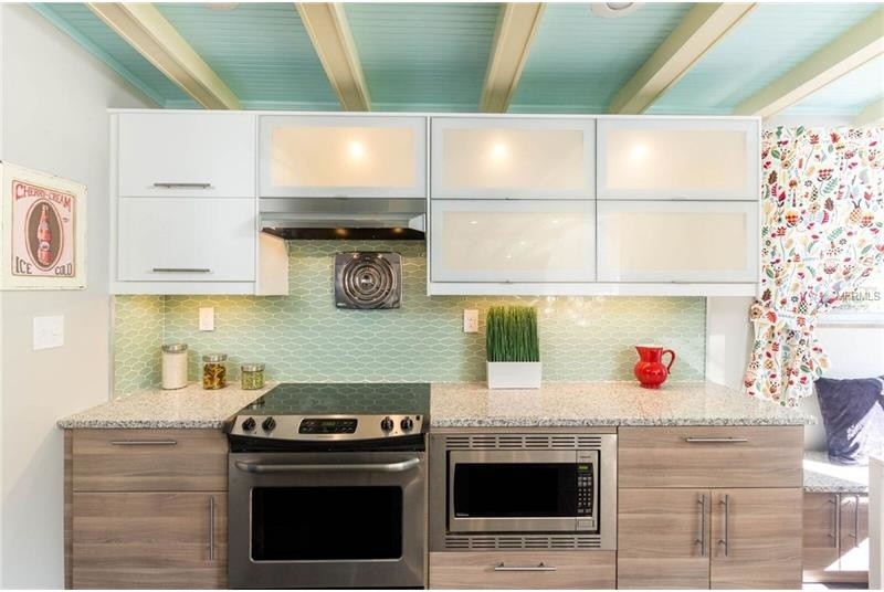 Foto di una cucina abitabile tradizionale di medie dimensioni con ante lisce, ante in legno bruno, top in granito, paraspruzzi verde e paraspruzzi con piastrelle di vetro