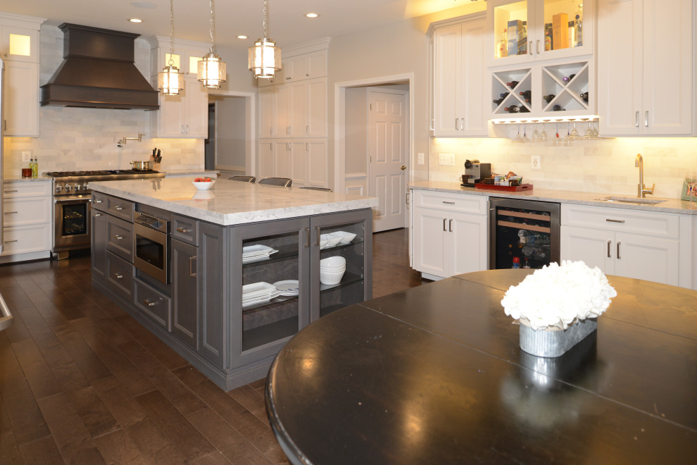 Inredning av ett modernt mellanstort vit vitt kök och matrum, med luckor med profilerade fronter, vita skåp, granitbänkskiva, vitt stänkskydd, rostfria vitvaror, en köksö och brunt golv