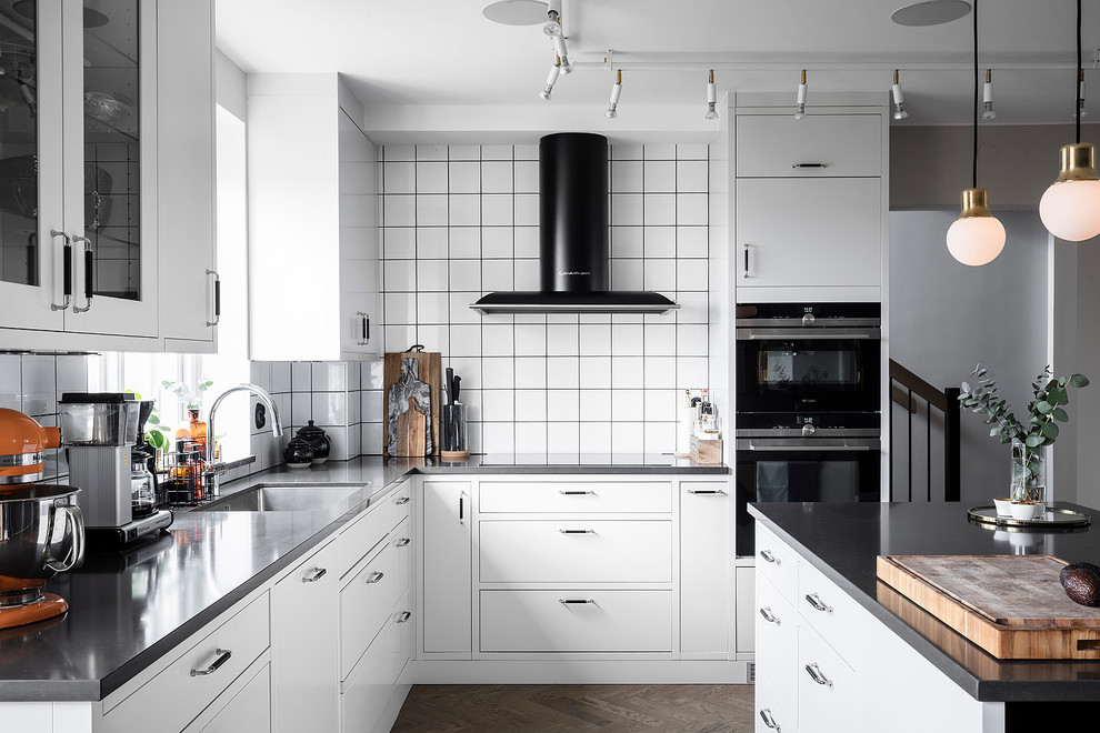 Immagine di una grande cucina scandinava con ante bianche, top in superficie solida, paraspruzzi bianco, paraspruzzi con piastrelle in ceramica, elettrodomestici in acciaio inossidabile, parquet scuro, pavimento marrone e top nero