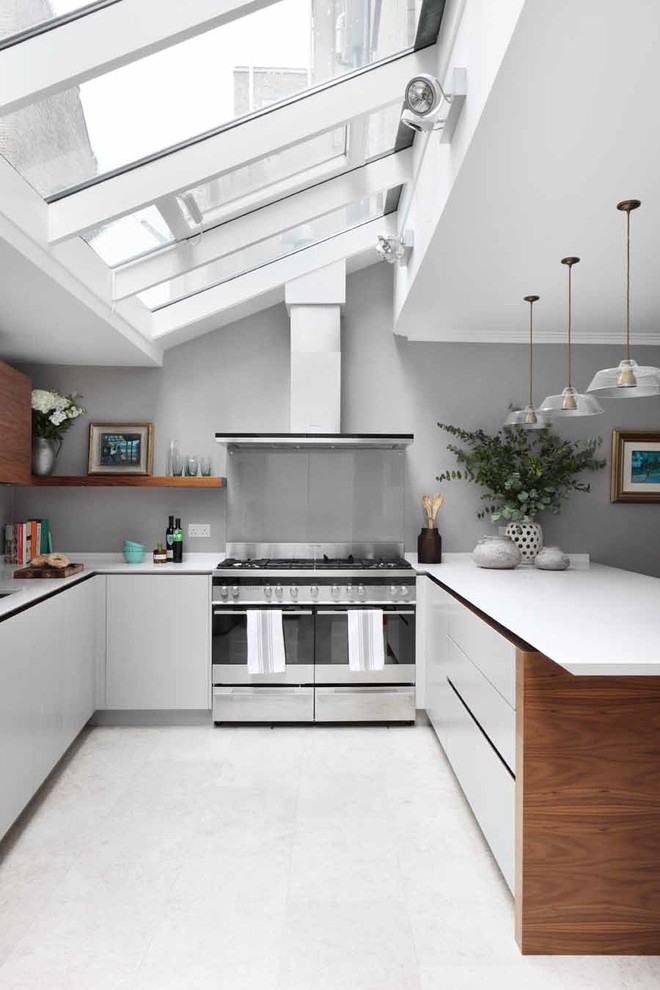 Idéer för ett modernt u-kök, med släta luckor, vita skåp, grått stänkskydd, glaspanel som stänkskydd, rostfria vitvaror, en halv köksö och vitt golv