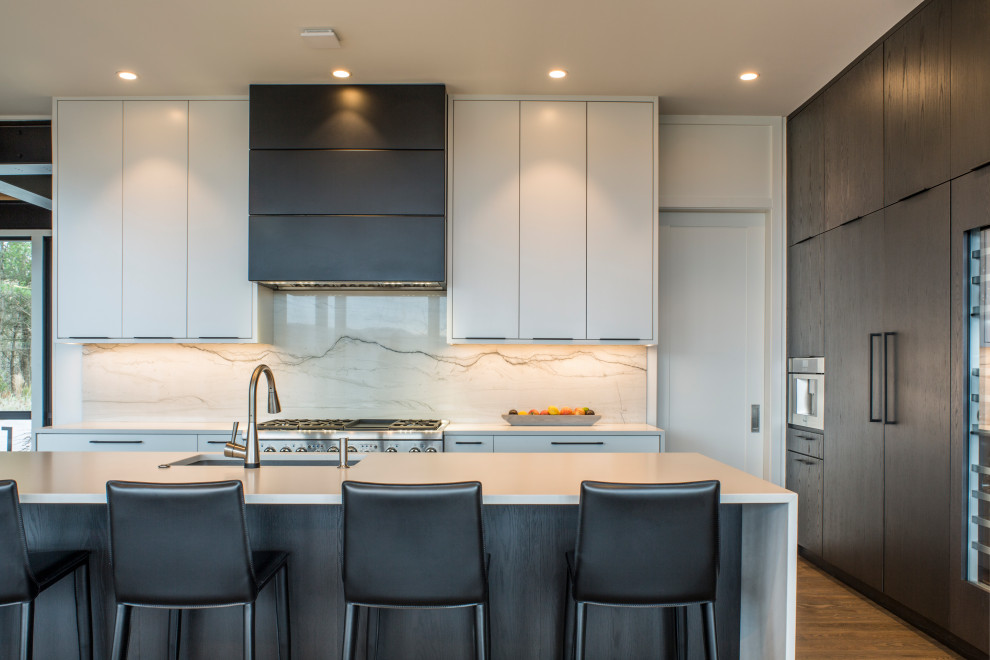 Large modern l-shaped kitchen/diner in Other with a single-bowl sink, flat-panel cabinets, dark wood cabinets, engineered stone countertops, grey splashback, stone slab splashback, integrated appliances, medium hardwood flooring, an island, brown floors and white worktops.