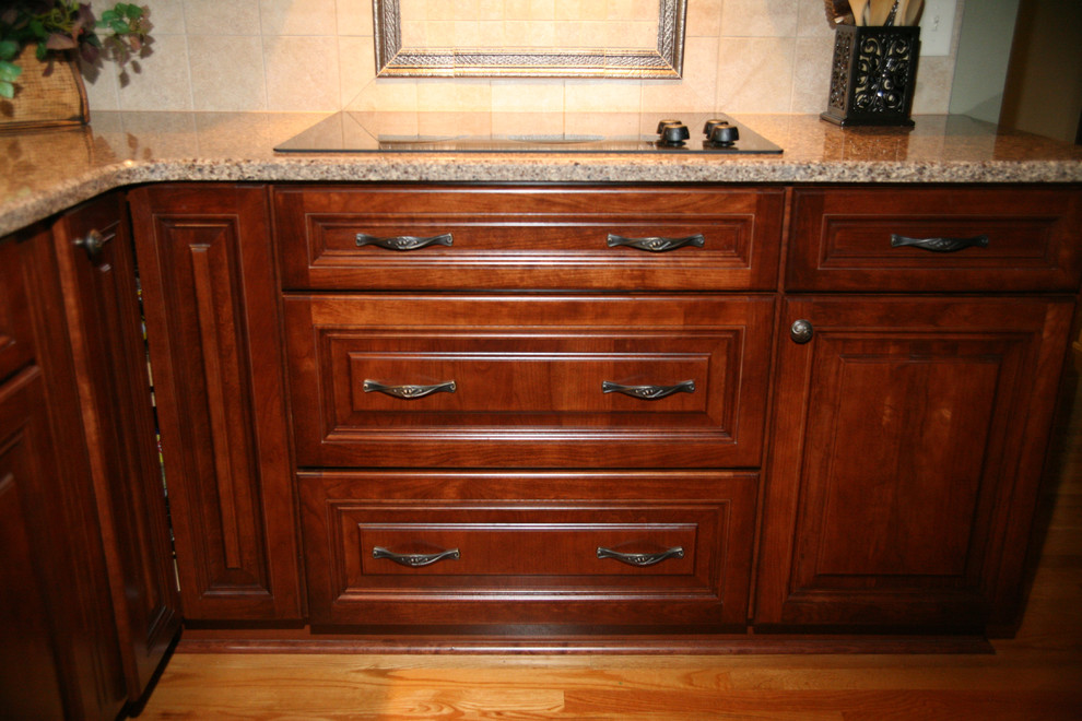 Foto på ett mellanstort vintage kök, med en dubbel diskho, luckor med upphöjd panel, skåp i mellenmörkt trä, beige stänkskydd, svarta vitvaror, mellanmörkt trägolv, bänkskiva i onyx, stänkskydd i glaskakel och brunt golv