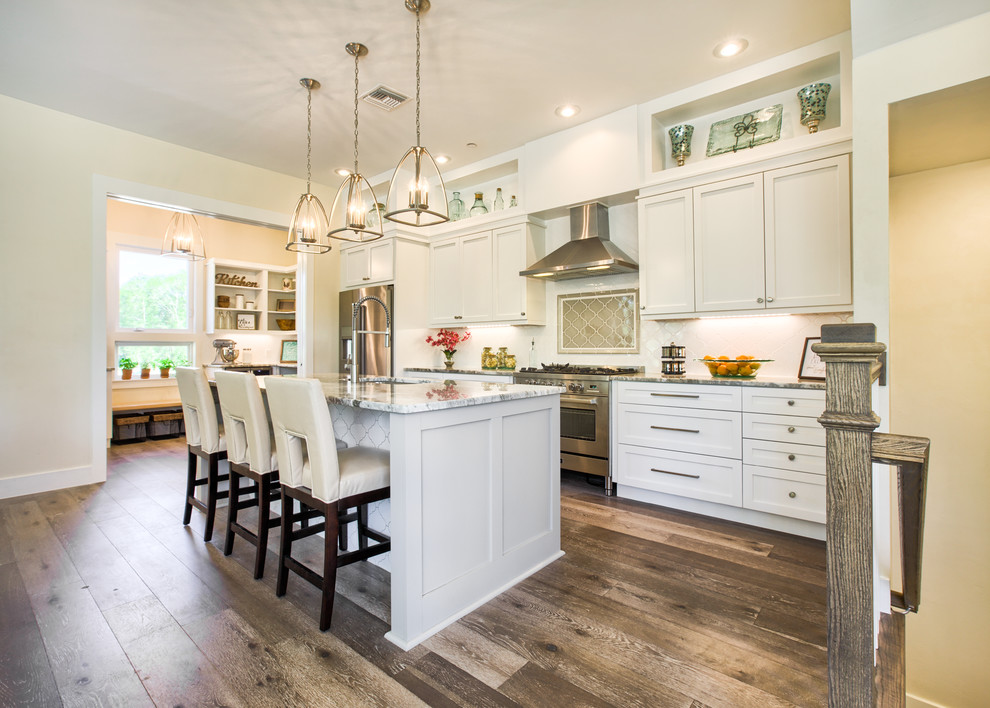 Large trendy galley medium tone wood floor and gray floor kitchen pantry photo in Other with an undermount sink, shaker cabinets, white cabinets, granite countertops, white backsplash, subway tile backsplash, stainless steel appliances and an island