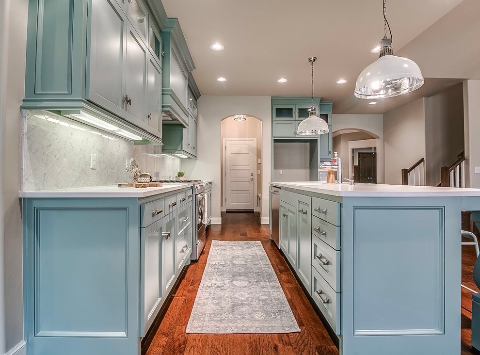 Design ideas for a medium sized traditional kitchen/diner in Oklahoma City with a single-bowl sink, blue cabinets, grey splashback, ceramic splashback, stainless steel appliances, medium hardwood flooring, an island, brown floors and engineered stone countertops.