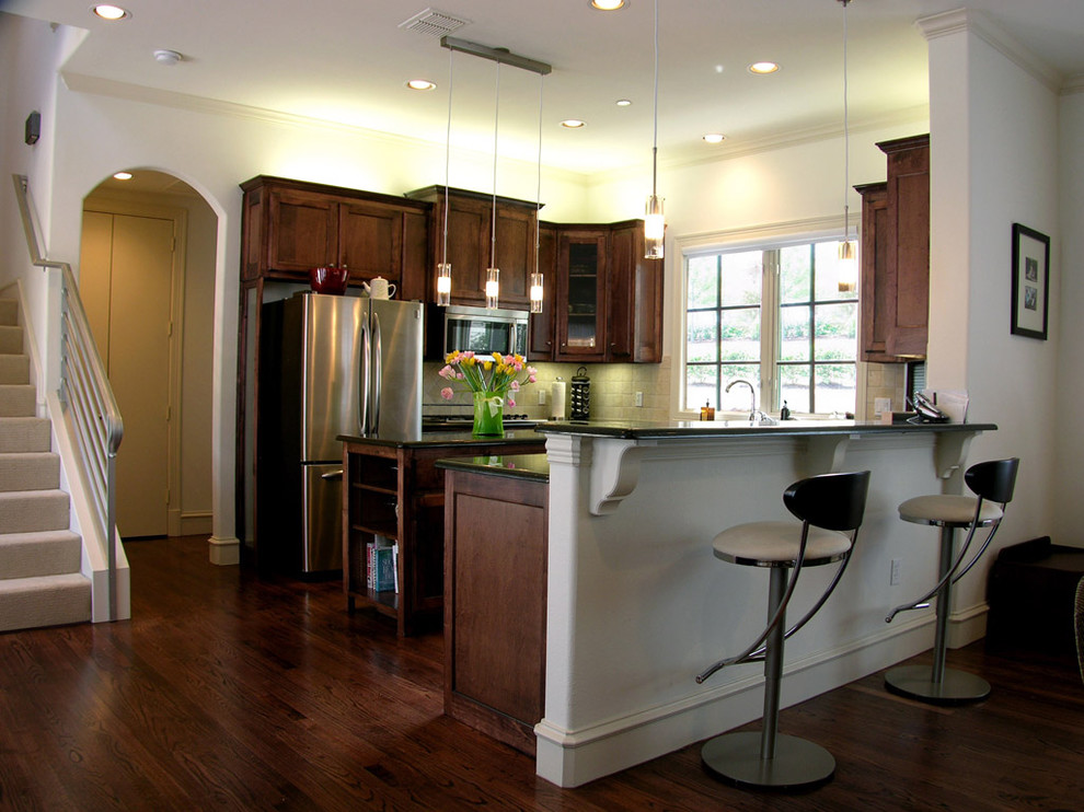 Example of a classic u-shaped kitchen design in Dallas with stainless steel appliances and dark wood cabinets