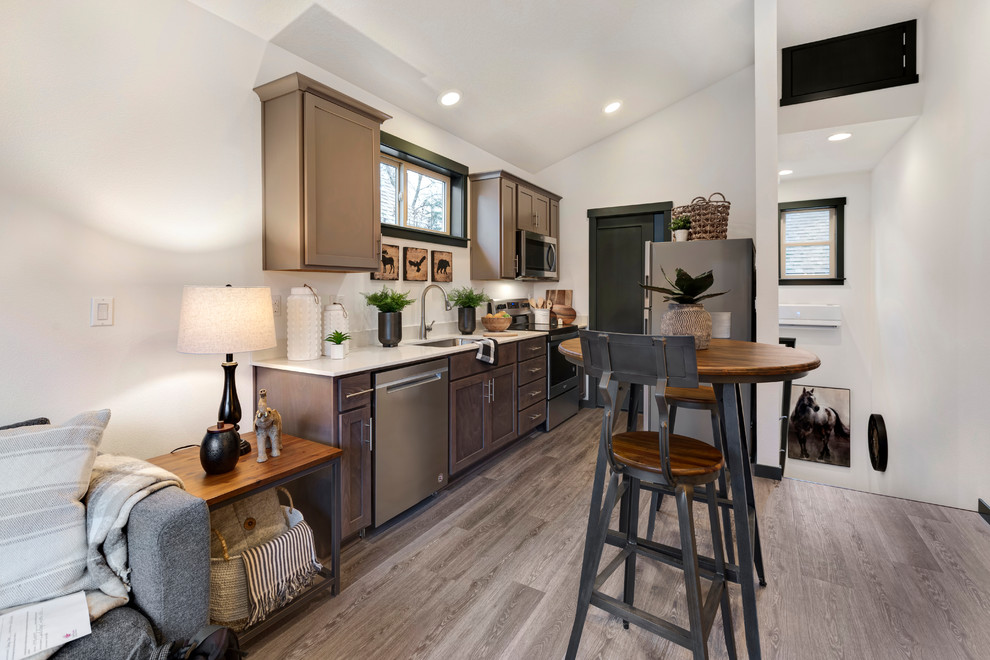 Ejemplo de cocina comedor moderna pequeña sin isla con fregadero de un seno, armarios estilo shaker, puertas de armario de madera en tonos medios, encimera de cuarzo compacto, salpicadero blanco, salpicadero de losas de piedra, electrodomésticos de acero inoxidable, suelo laminado, suelo gris y encimeras blancas