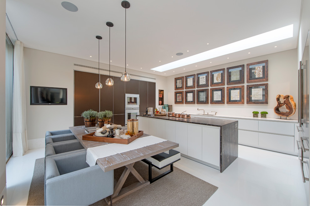 Moderne Wohnküche mit Unterbauwaschbecken, flächenbündigen Schrankfronten, weißen Schränken, weißen Elektrogeräten, Kücheninsel und weißem Boden in London