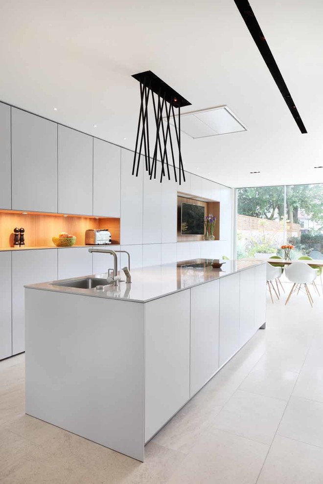 Inspiration for a medium sized contemporary single-wall open plan kitchen in London with an integrated sink, flat-panel cabinets, white cabinets, engineered stone countertops, stainless steel appliances, porcelain flooring and an island.