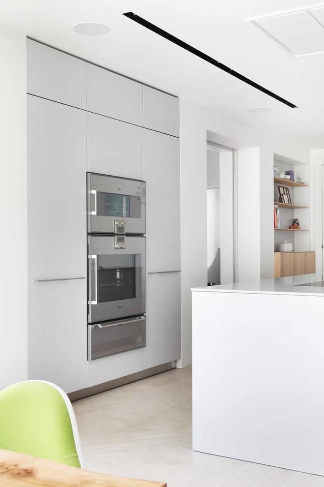 Inspiration för mellanstora moderna linjära kök med öppen planlösning, med en integrerad diskho, släta luckor, vita skåp, bänkskiva i kvarts, rostfria vitvaror, klinkergolv i porslin och en köksö