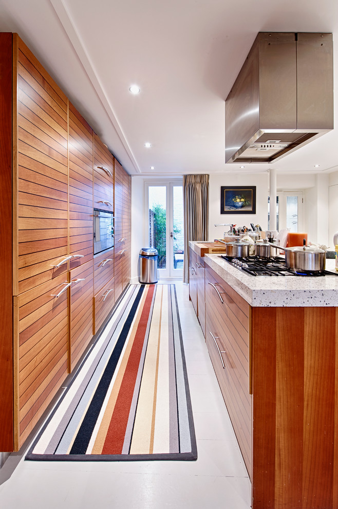 Inspiration for a large traditional single-wall kitchen/diner in London with an integrated sink, flat-panel cabinets, medium wood cabinets, granite worktops, stainless steel appliances, painted wood flooring and an island.