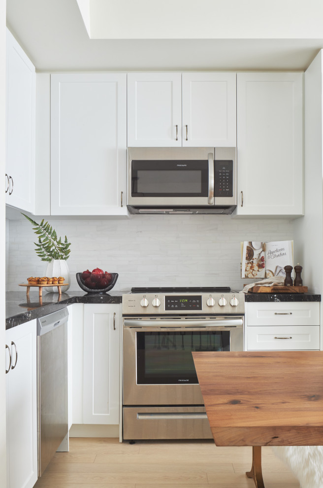 Kleine Skandinavische Wohnküche ohne Insel mit Schrankfronten im Shaker-Stil, weißen Schränken, Granit-Arbeitsplatte, Küchenrückwand in Weiß und schwarzer Arbeitsplatte in Toronto